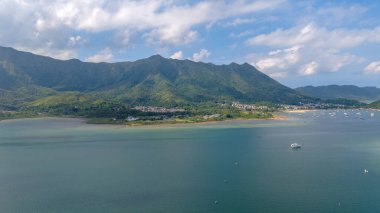 Etrafı yemyeşil dağlarla çevrili sakin bir sahil şeridi sergileniyor.