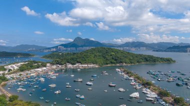 Liman çeşitli teknelerle dolu, mavi bir gökyüzünün altında, çevrili.