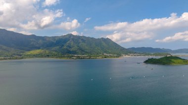 Etrafı yemyeşil dağlarla çevrili sakin bir sahil şeridi sergileniyor.