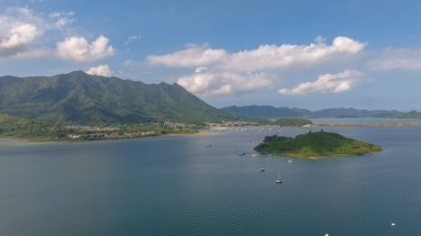 Etrafı yemyeşil dağlarla çevrili sakin bir sahil şeridi sergileniyor.