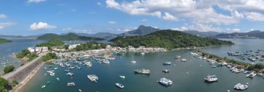 Liman çeşitli teknelerle dolu, mavi bir gökyüzünün altında, çevrili.