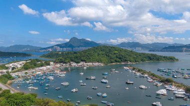 Liman çeşitli teknelerle dolu, mavi bir gökyüzünün altında, çevrili.