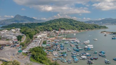 Liman çeşitli teknelerle dolu, mavi bir gökyüzünün altında, çevrili.