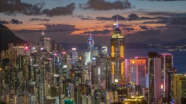 Gün batımında Hong Kong 'un aydınlık gökdelenleri canlı şehirleri gösteriyor.