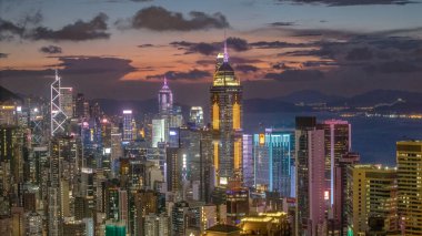 Gün batımında Hong Kong 'un aydınlık gökdelenleri canlı şehirleri gösteriyor.
