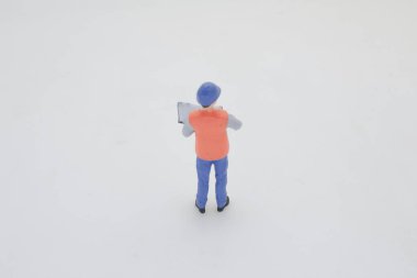 Yelekli bir inşaat işçisinin minyatür figürü.,