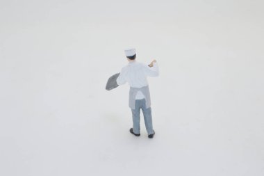 Beyaz arka planda duran küçük bir şef modeli.