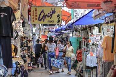 Kalabalık bir açık hava piyasa sahnesi. Yürüyen ve alışveriş yapan insanlar.