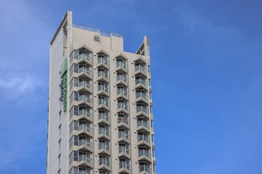 Ayırt edici balkonları ve modern mimarisi olan uzun apartman kulesi.