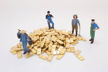 Altın külçelerinin etrafında duran işçi heykelcikleri