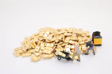 Üç minyatür figür aletleri kullanarak altın külçeleri hareket ettiriyor