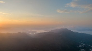 Güneşin doğuşu sisli bir tepenin ve sahil şeridinin üzerinde