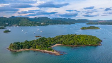 Bereketli yeşil adalar ve sakin mavi deniz manzaralı bir sahil şeridi.