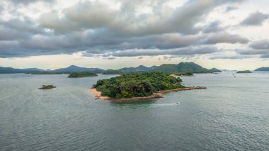 Bereketli yeşil adalar ve sakin mavi deniz manzaralı bir sahil şeridi.