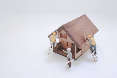 Minyatür heykelcikler, iki ahşap ev şeklindeki modeli inşa etmek için işbirliği yapıyorlar.