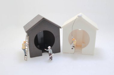 Minyatür heykelcikler, iki ahşap ev şeklindeki modeli inşa etmek için işbirliği yapıyorlar.