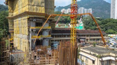 Sarı kaplamalı bir bina ve vinçlerin bulunduğu aktif bir inşaat alanı.