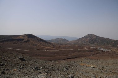Dağılmış kayalar ve alçak bitki örtüsüyle geniş çorak bir arazi.