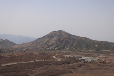 Dağılmış kayalar ve alçak bitki örtüsüyle geniş çorak bir arazi.