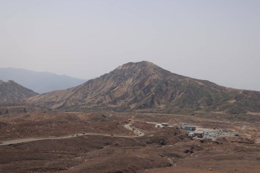 Dağılmış kayalar ve alçak bitki örtüsüyle geniş çorak bir arazi.