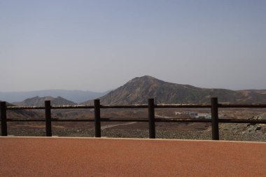 Dağılmış kayalar ve alçak bitki örtüsüyle geniş çorak bir arazi.