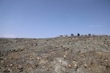 Dağılmış kayalar ve alçak bitki örtüsüyle geniş çorak bir arazi.