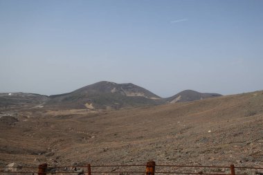 Dağılmış kayalar ve alçak bitki örtüsüyle geniş çorak bir arazi.