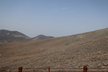 Dağılmış kayalar ve alçak bitki örtüsüyle geniş çorak bir arazi.