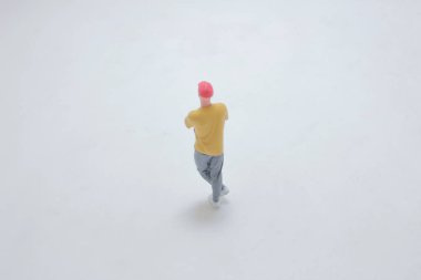 Beyaz bir yüzeyde duran bir insanın minyatür figürü, detaylarıyla ele geçirilmiş..