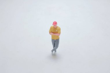 Beyaz bir yüzeyde duran bir insanın minyatür figürü, detaylarıyla ele geçirilmiş..