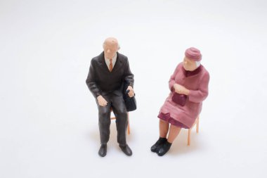 Oturan yaşlı bir adam ve kadını resmeden iki küçük heykel.