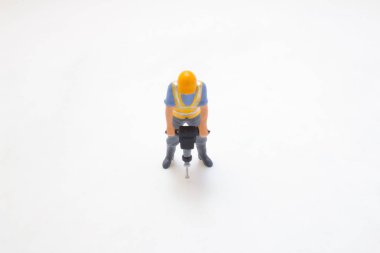 Minyatür bir inşaat işçisi figürü odaklanmış, çalışıyor