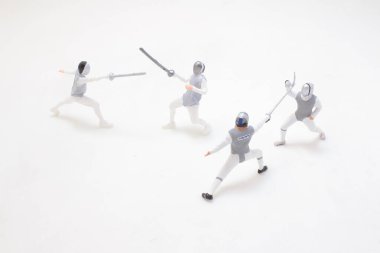 Dört detaylı minyatür eskrim figürü aktif olarak bir kibrit düzeninde poz veriyor,