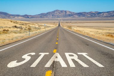 Uzakta dağlar ve asfalt üzerinde START boyalı uzun, düz kırsal karayolu
