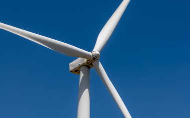 Derin mavi gökyüzüne karşı izole edilmiş üç neşter rüzgarı türbini; Kuzey İsrail 'deki Golan Tepeleri' nde çekilmiş bir fotoğraf