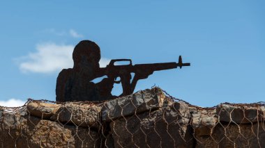 Suriye 'ye tepeden bakan Bental Dağı' nın tepesinde ve Golan Tepeleri 'ndeki İsrail sınırında siluet giymiş bir askerin metal kesimi.