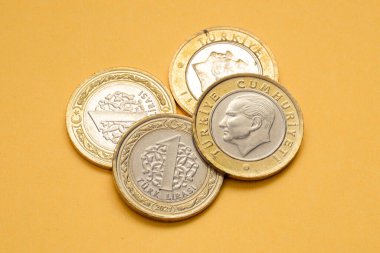 Front and back view of a 1 Turkish Lira Coin on a yellow background.