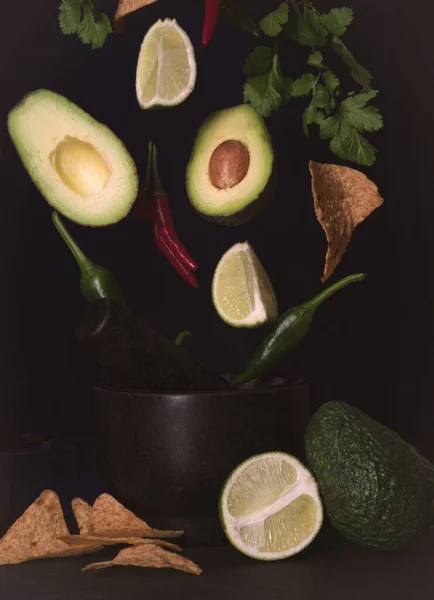Avokado ve kireç bir kasede yüzen siyah bir arka planda sonbahar havası şili cipsleri çıtır çıtır guacamole
