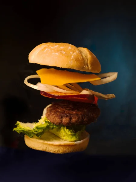 burger with beef, tomato and lettuce on black background ,cheese, onion tomato floating ,fall from sky