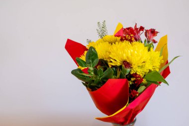 Kırmızı ve sarı buket çiçek aranjmanı kırmızı ve sarı ambalaj kağıtlarıyla