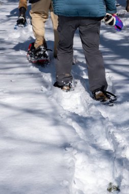 Karla kaplı bir patikada kar ayakkabısı. Kar ayakkabılarının bıraktığı izlere odaklanarak..