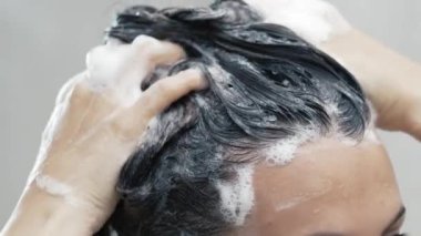 Kadın duş alıyor, saçını yıkıyor.