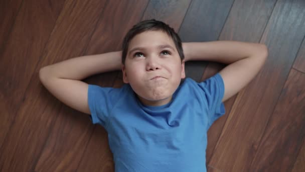 Усміхнений Хлопчик Лежить Підлозі Мріє — стокове відео