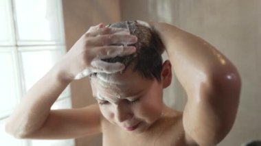 Çocuk duş alıyor, saçını yıkıyor.