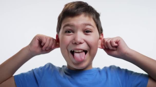 子供は顔を作って舌を見せる 白地に隔離された — ストック動画