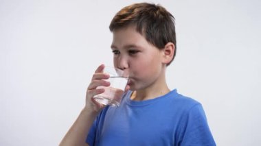 Beyaz arka planda camdan su içen çocuk