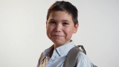 Beyaz arka planda çantasıyla gülümseyen öğrenci.