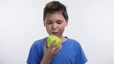 Beyaz arka planda yeşil elma yiyen çocuk