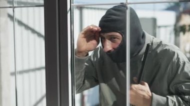 Levyeli bir hırsız evin camına bakıyor.