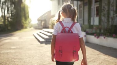 Pembe sırt çantalı küçük kız okula gidiyor.